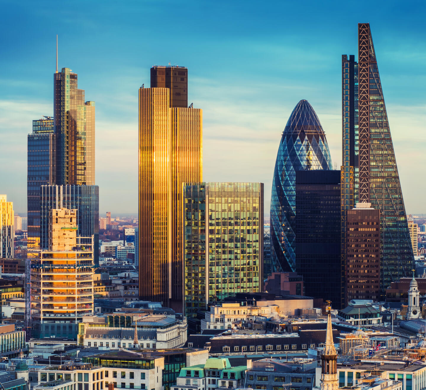 London, United Kingdom - The bank district of central London with famous skyscrapers in golden shine and other landmarks at sunset with blue sky